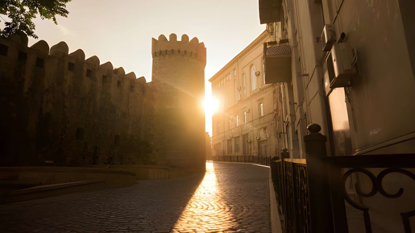 A street in Icherisheher at sunrise, the old wall and a tower against the sun